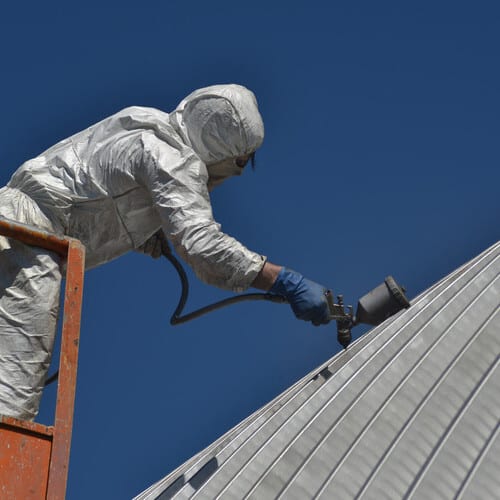 worker applying a metal roof coating