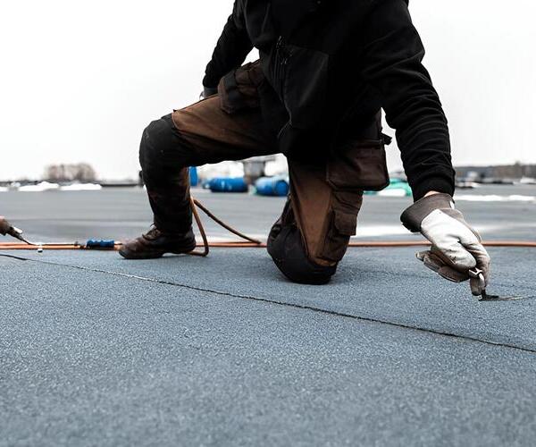 worker applying a modified bitumen roofing system